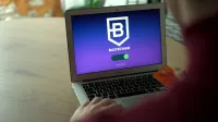 Person using laptop displaying blockchain login screen while holding card.