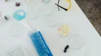 Aerial view of laboratory equipment including petri dishes, pills, test tubes, and syringes.