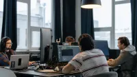 Team of developers working together on computers in a modern tech office.