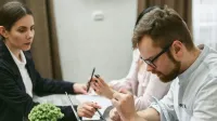 Three professionals engage in a collaborative meeting, discussing ideas over a laptop in an office setting.