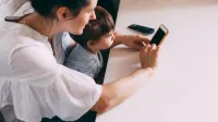 A mother and her child engaging with a smartphone indoors. Perfect for family and technology themes.