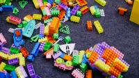 Vibrant plastic toy blocks scattered on a grey carpet, showcasing assorted shapes and colors.