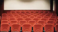 A spacious theater with empty red seats and a large screen, ready for the next audience.