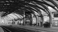 Imagen en blanco y negro de una plataforma de estación de tren vacía con un diseño arquitectónico moderno.