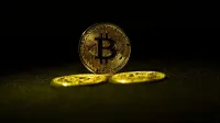 Golden Bitcoin coins symbolizing cryptocurrency wealth on a dark background.
