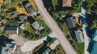Aerial top view of house rooftops on green valley land with roadway in remote rural village