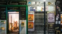 Charming vintage storefront with warm interior lighting and colorful street posters at night.