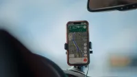 A smartphone with GPS navigation app mounted on a car dashboard during a road trip.