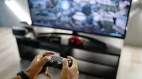 Close-up de manos sosteniendo un controlador de juegos mientras juega videojuegos en interiores.