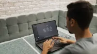 A man working on a laptop in a cozy, modern office space with a focus on technology.