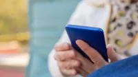 Senior adult using a smartphone outdoors on a sunny day. Focus on hands and device.