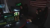Cybersecurity professionals working on computer systems, focusing on data protection in a dimly lit room.