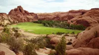 Explore las impresionantes formaciones de roca roja y el exuberante valle en el paisaje desértico de Utah.
