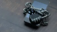 Close-up of a smartphone wrapped in a chain with a padlock, symbolizing strong security.