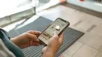 Close-up of hands holding a smartphone displaying an online shopping app in an indoor setting.