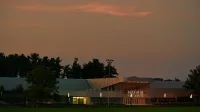 The Kunn Ice Arena illuminated in the early evening, set against a moody sky in East Lansing, Michigan.