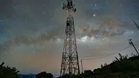 A communication tower silhouetted against a stunning starry night sky with the Milky Way.