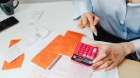 La empresaria calcula los gastos usando recibos y calculadora en el escritorio. Ideal para finanzas, temas contables.