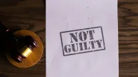A courtroom document labeled 'Not Guilty' beside a gavel symbolizes justice.