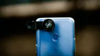 Zoom optical lens attached to camera of modern smartphone against blurred background in daytime