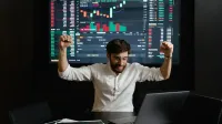 El empresario celebra el éxito del mercado de valores con las manos levantadas de emoción en una mesa de negociación.
