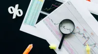 High-angle view of financial charts, showcasing stock market analysis with magnifying glass and highlighters.