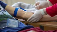Healthcare professional drawing blood from a patient in a medical setting.