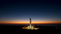 A powerful rocket stands ready on its launch pad against a stunning twilight sky.