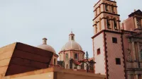 View of neoclassical church domes and tower in Tequisquiapan, Mexico, against a clear sky.