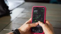 A person holding a smartphone with a stock market app displaying analytics and stock prices.