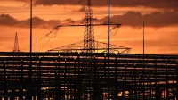 Silhouetted electric tower against vivid sunset sky, highlighting urban infrastructure.