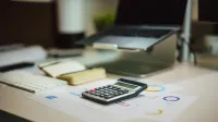A modern workspace with a laptop, calculator, and documents on a desk, perfect for finance tasks.