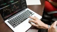 Close-up de la mano usando laptop para el análisis del mercado de valores en el entorno de la oficina.