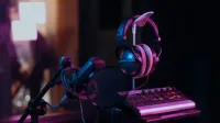 High-quality audio recording studio setup with a microphone, headphones, and mixer board in dim lighting.