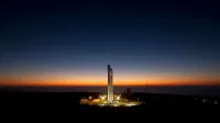 A powerful rocket stands ready on its launch pad against a stunning twilight sky.