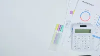 Minimalist office desk with a calculator, budget planning documents, and colorful pens.
