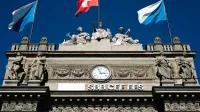 Edificio histórico SBB con banderas suizas y esculturas en Zúrich.