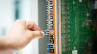 An individual connecting a cable into a network server port indoors, focusing on technology setup.