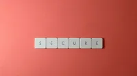 A close-up of the word 'Secure' spelled out with tiles on a red surface, ideal for security concepts.