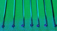 Vivid and detailed close-up of a patterned silicon wafer with vibrant green and blue colors.