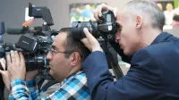 Photographers focusing on event coverage with advanced cameras indoors, showcasing media professionals in action.