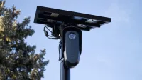 A solar-powered outdoor surveillance camera mounted on a pole, capturing clear day images.