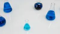 Various glass flasks filled with blue liquid in a scientific setting, perfect for research themes.