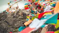 Vibrant Tibetan prayer flags fluttering on a rocky hillside in Garzê, China.