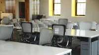 Spacious open office workspace with desks, chairs, and natural lighting.