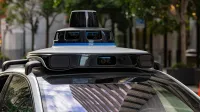Detailed view of sensors atop an autonomous car, showcasing advanced technology in an urban setting.