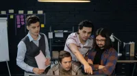 Group of professionals discussing a project at a computer in a modern office environment.