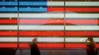 Silhouetted men posing and photographing against a neon-lit American flag background.