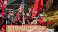 People celebrate with flags during a Chinatown parade, showcasing a blend of American and Chinese culture.