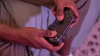Manos agarrando un controlador de juego, involucrado en un videojuego en interiores.